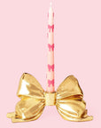 A gold bow shaped taper candle holder. 