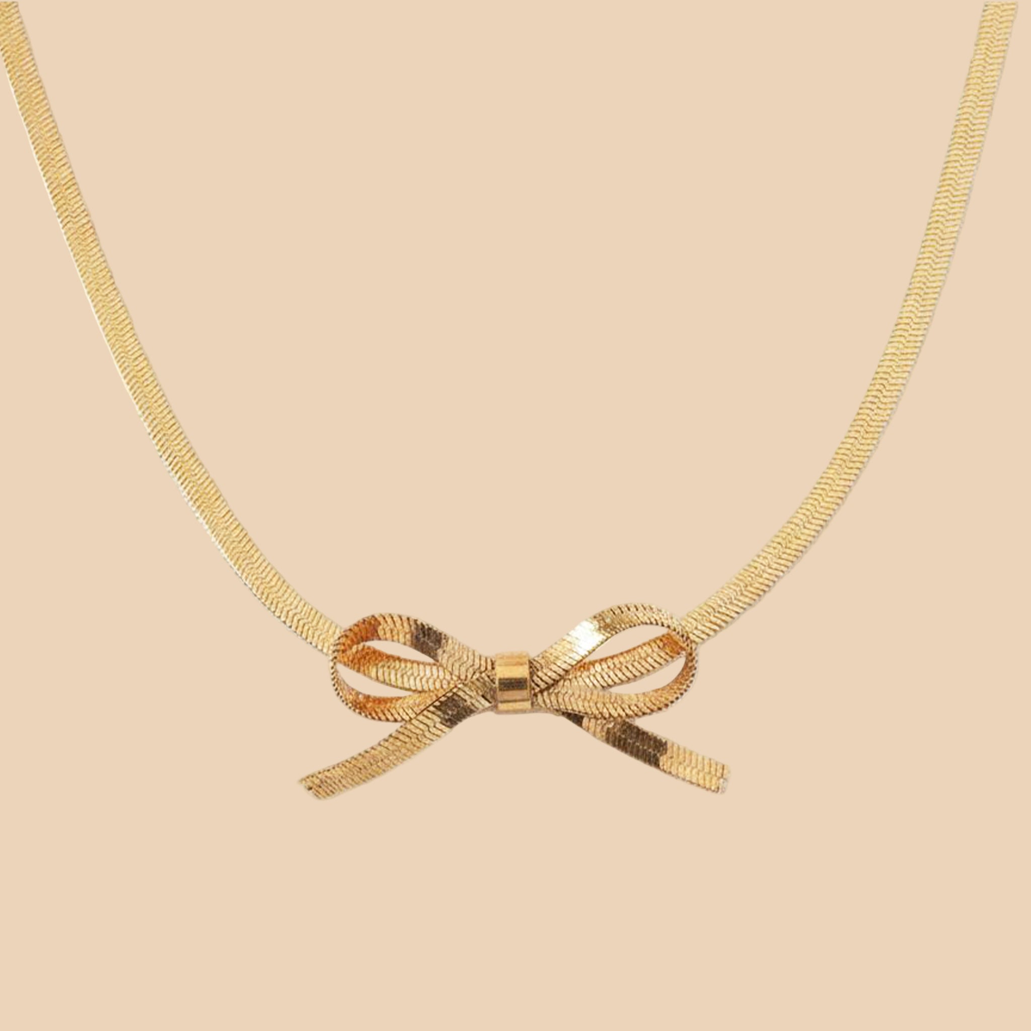 A gold herringbone chain necklace tied in a bow. 