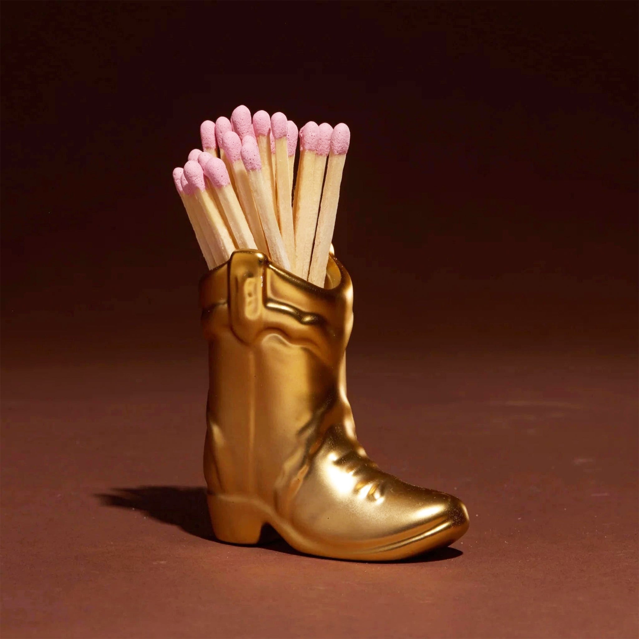 A gold ceramic cowboy boot match holder. 