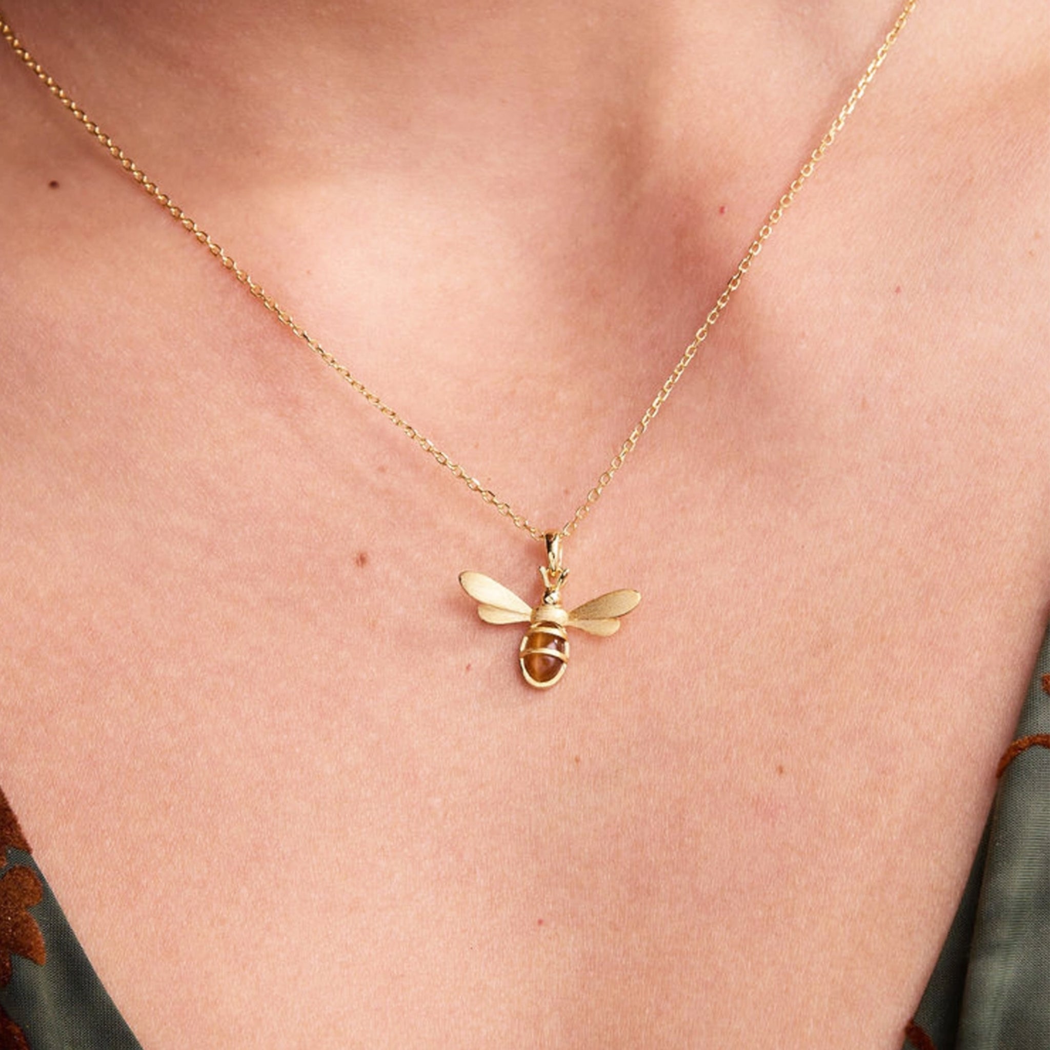 A gold bee pendant necklace. 