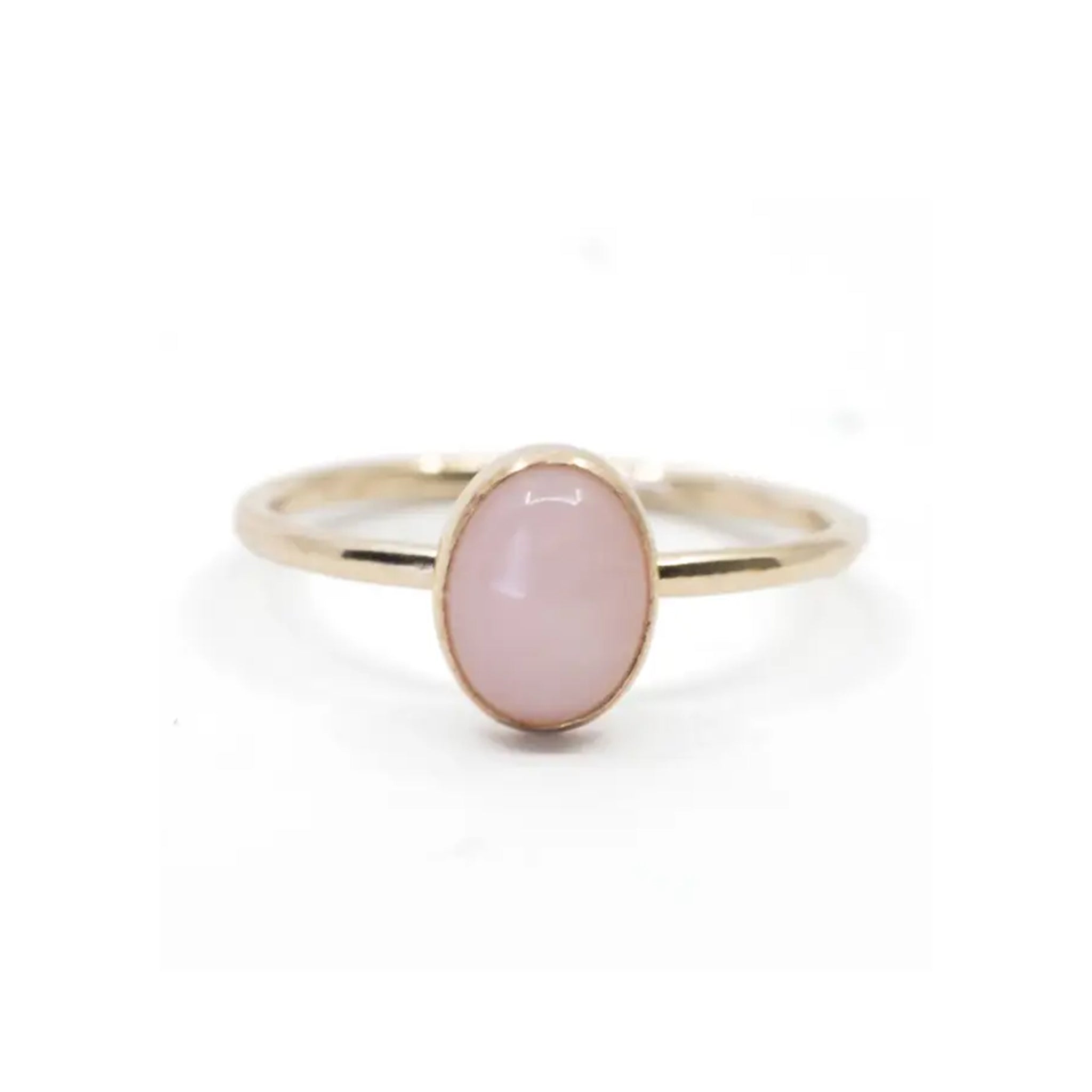 A gold ring with a pink oval opal stone in the center. 