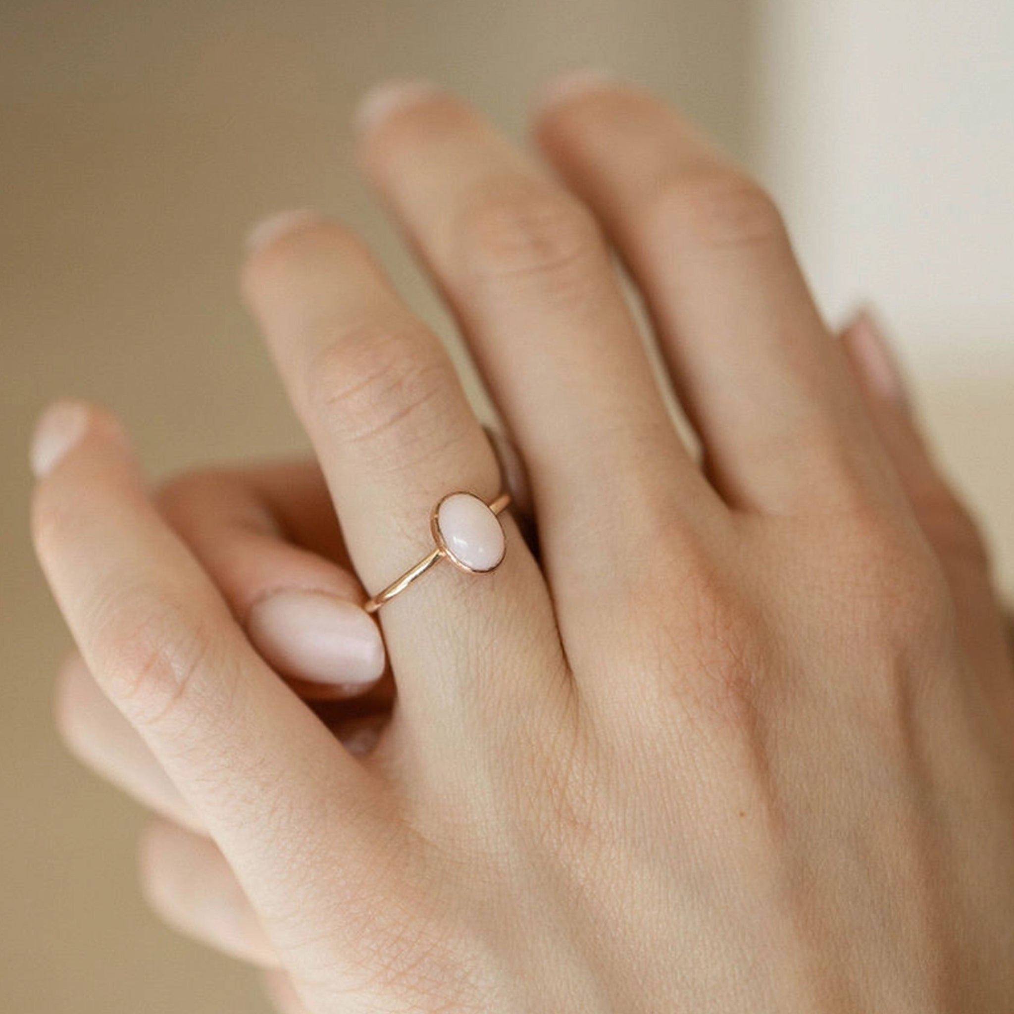 A gold ring with a pink oval opal stone in the center. 