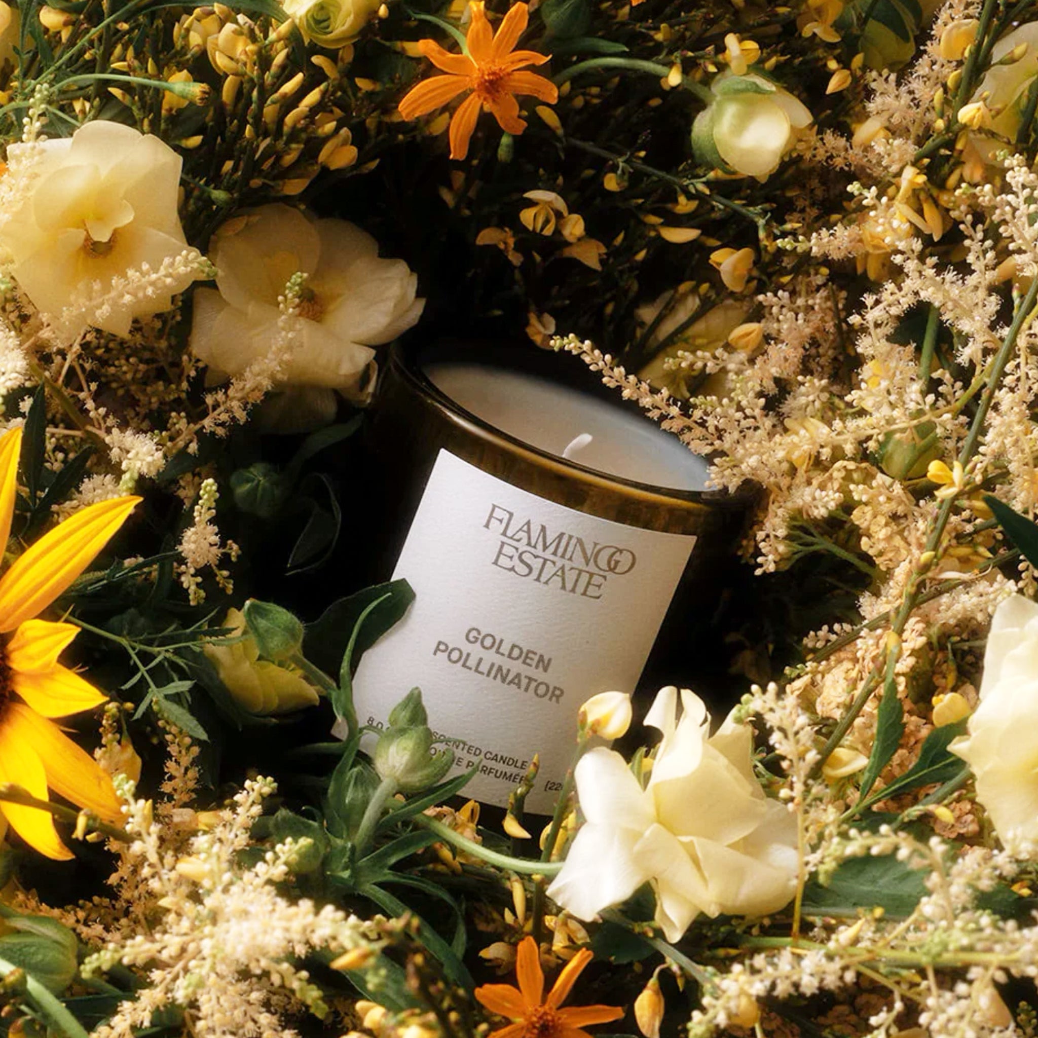 Flamingo Estate candle surrounded by a bouquet of flowers