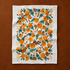 A white tea towel with an orange floral print. 