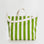 On a white background is a green and white canvas tote bag with two hand straps and one larger over the shoulder option. 