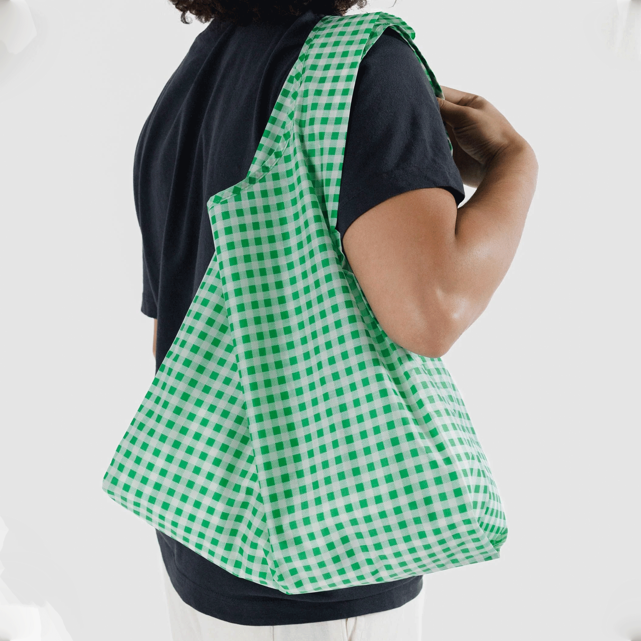 A model wearing a green and white gingham printed nylon tote bag. 