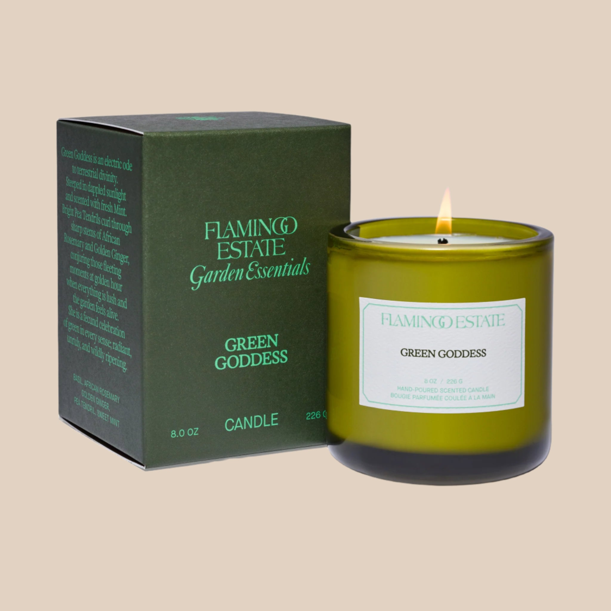 A green glass candle with a white label that reads, 'Flamingo Estate Green Goddess'. 