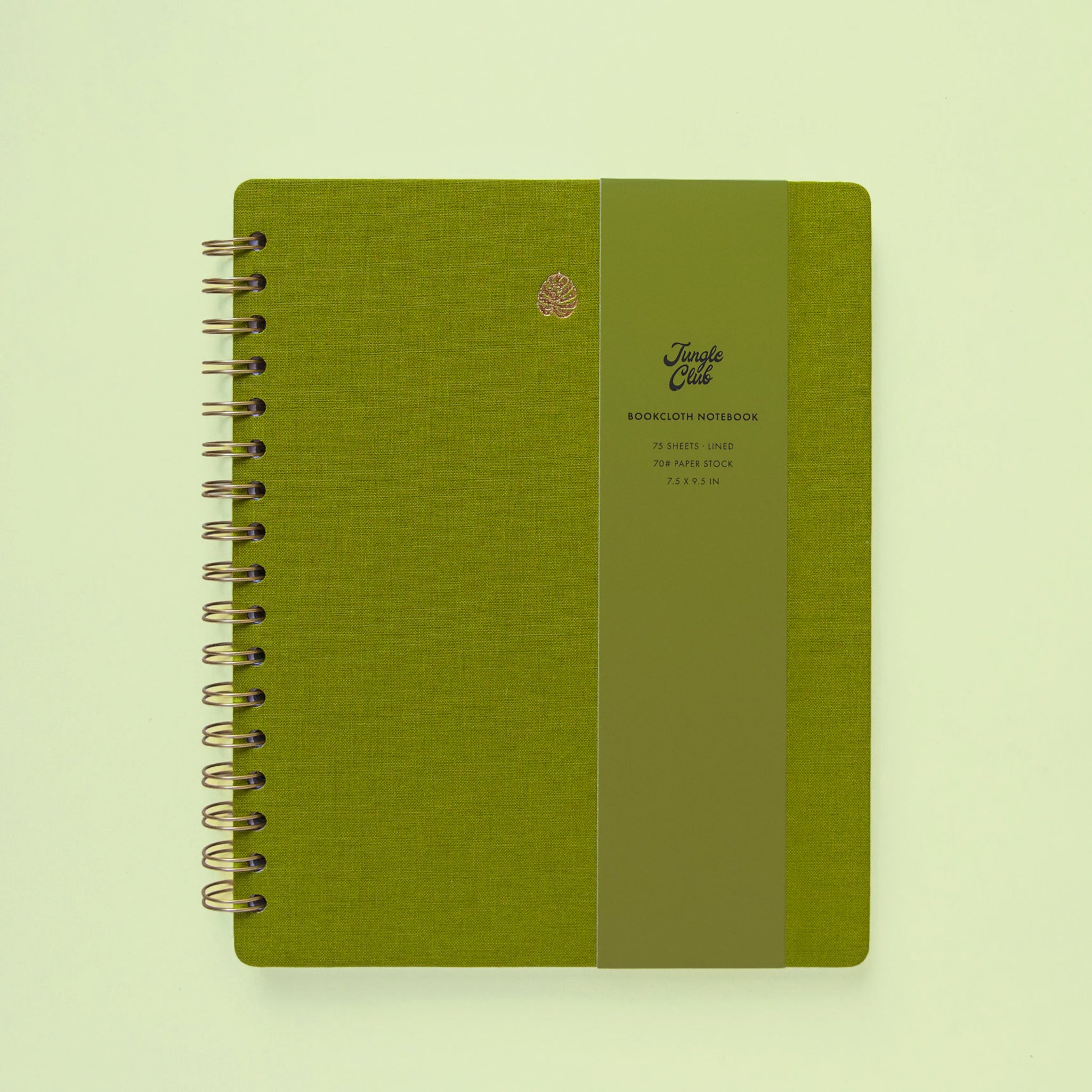 A green notebook with spiral binding and a gold foiled monstera leaf in the top center. 