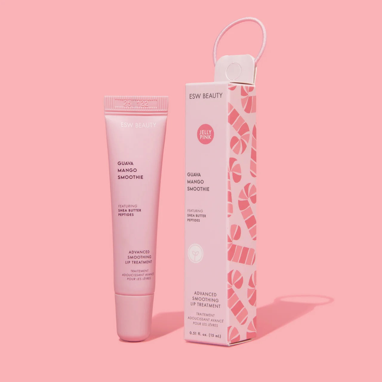 Light pink ESW Beauty ‘Guava Mango Smoothie’ lip treatment tube standing beside its matching candy-cane patterned box with a loop handle on a pastel pink background.