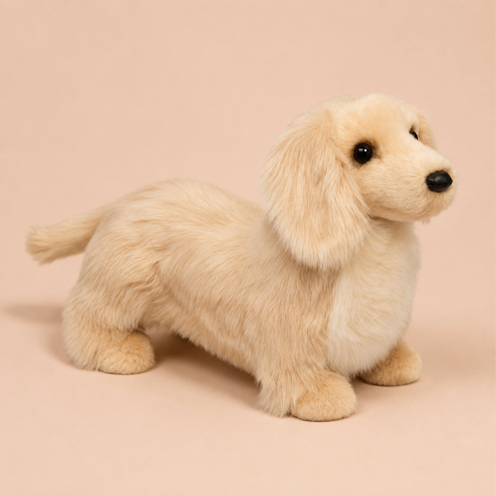 A golden long haired dachshund shaped stuffed animal toy. 