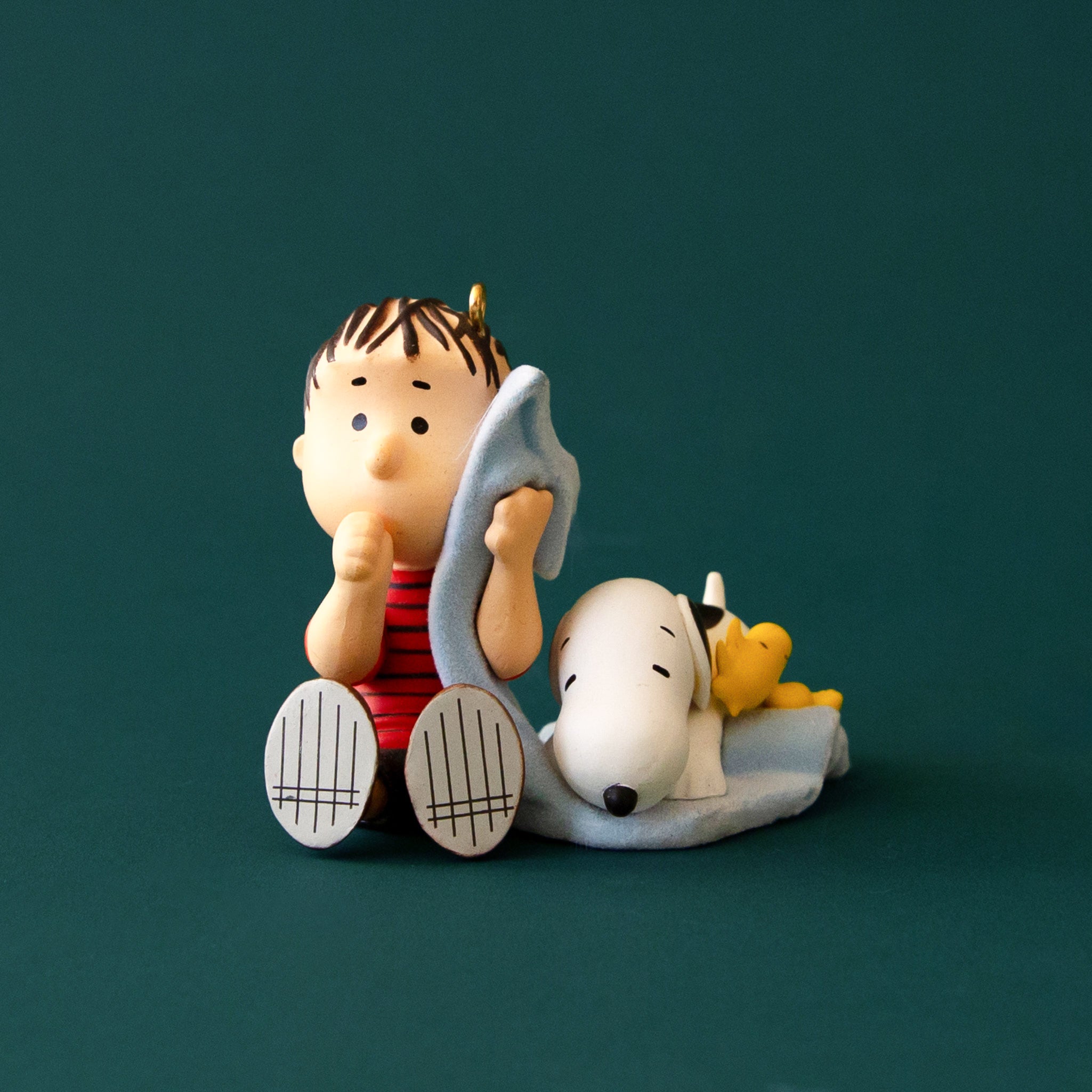 An ornament of Linus and Snoopy with his light blue blanket. 