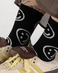 A pair of black socks with white smiley faces on them.