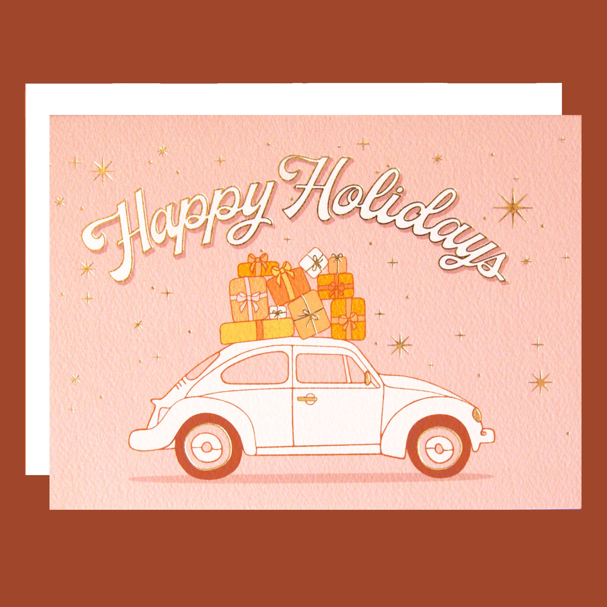 On a burnt orange background is a card with a VW bug with gifts on top and text arched above it that reads, "Happy Holidays".