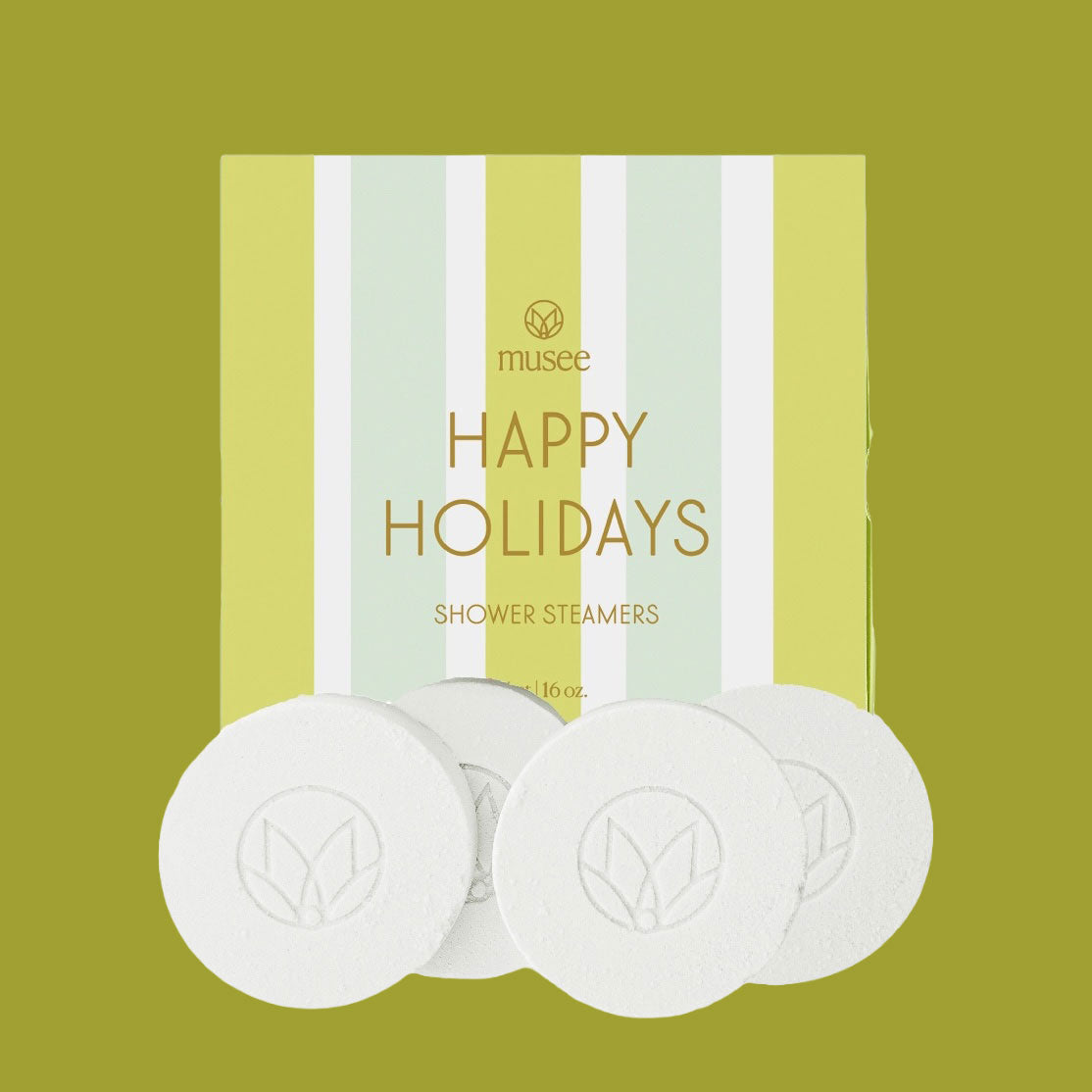 A box of Musee “Happy Holidays” Shower Steamers with pale green, white, and yellow vertical stripes is shown against an olive-green background. Four white round steamers sit in front of the box.