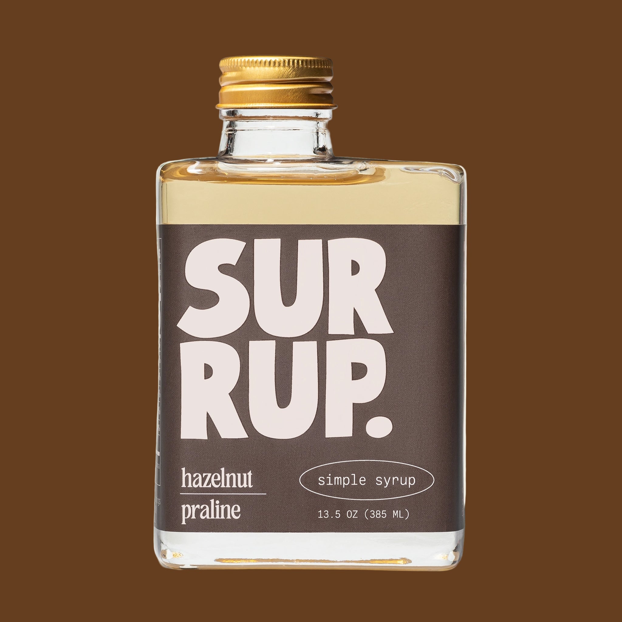 A glass rectangle bottle of syrup with text that reads, "Surrup. hazelnut praline simple syrup". 