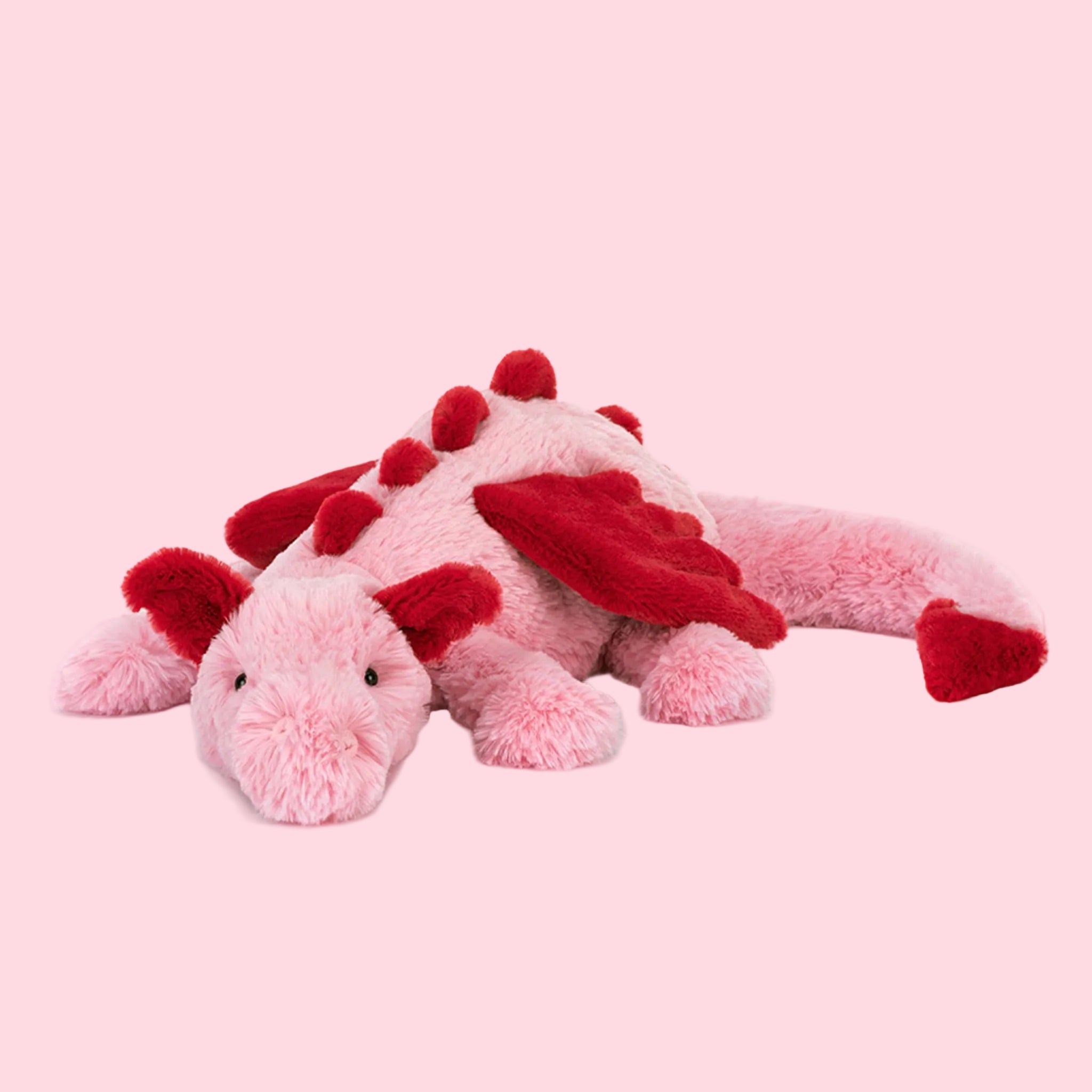 A pink and red dragon shaped stuffed animal. 