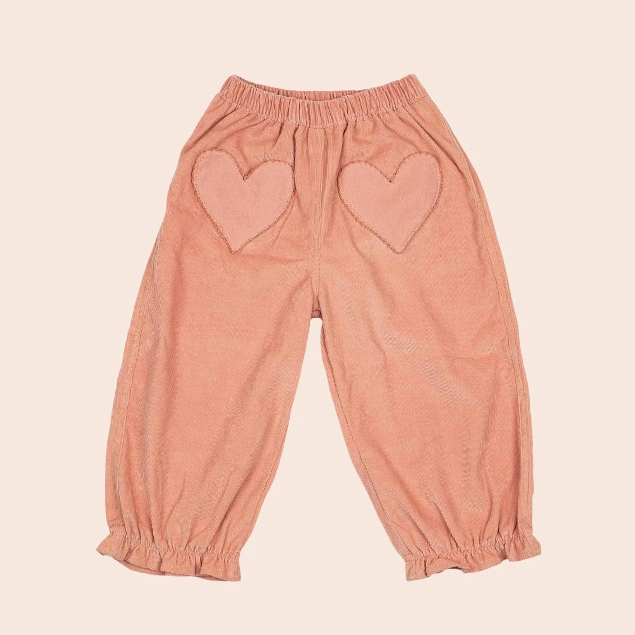 A pair of pink children's pants with heart shaped pockets. 