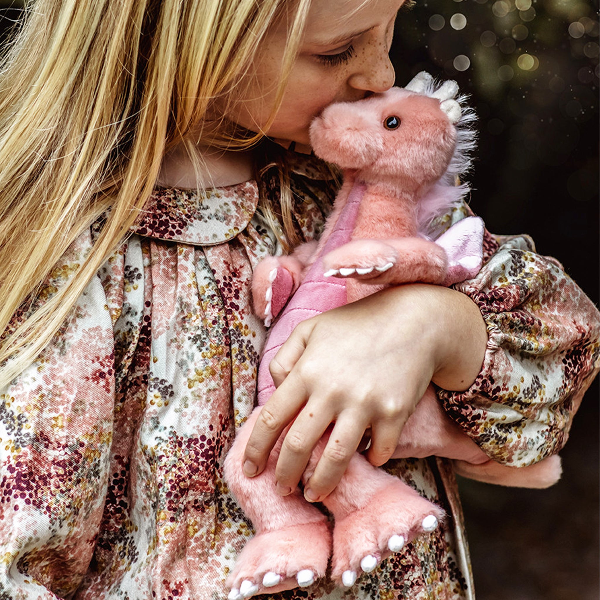 A pink dragon shaped stuffed animal toy. 