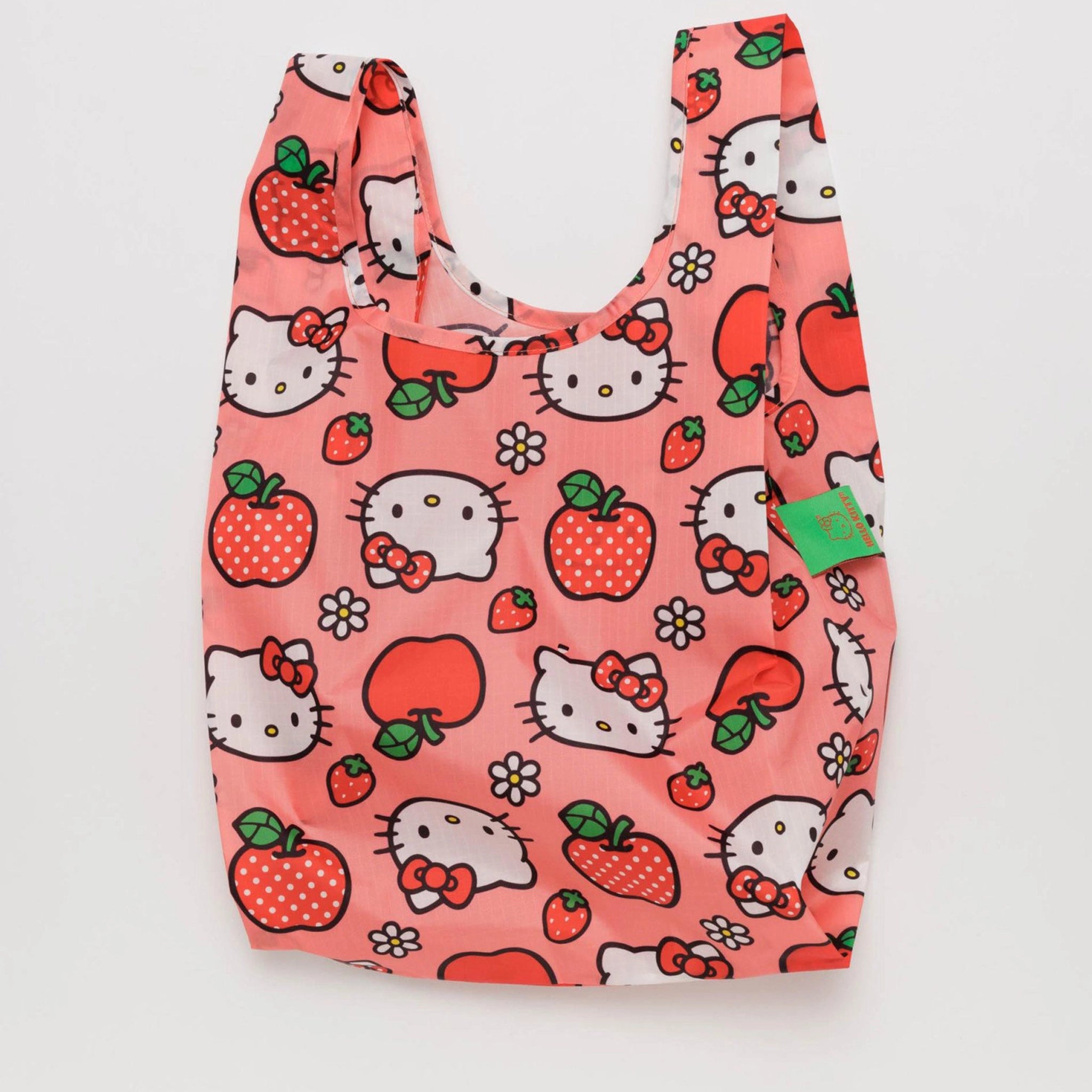 On a white background is a pink nylon bag with hello kitty and apple designs all over. 