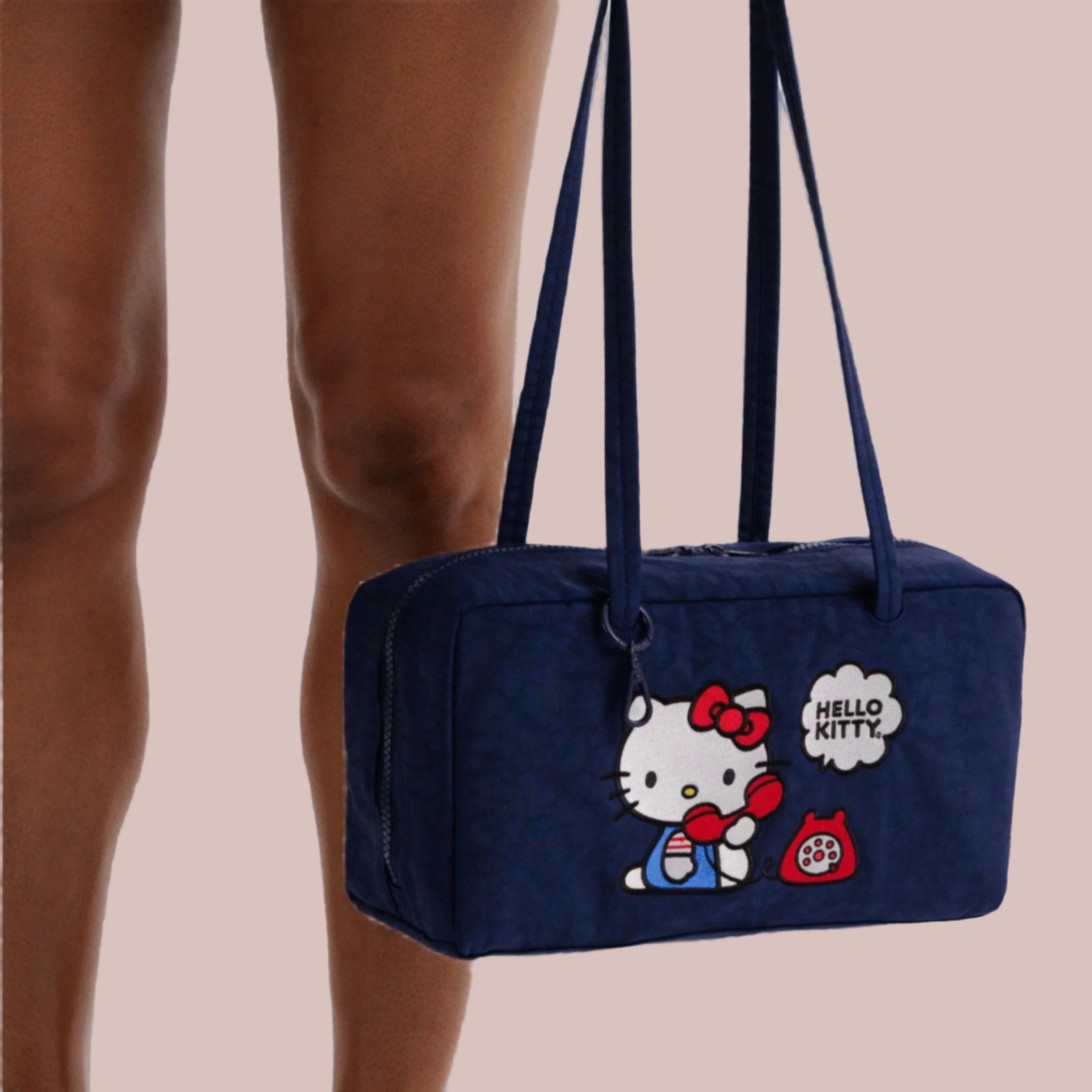 A dark blue nylon handbag with an embroidered hello kitty design. 