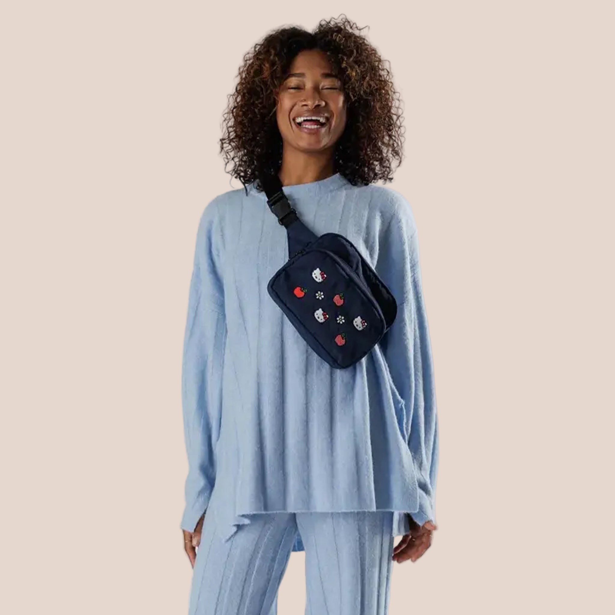 A dark blue nylon fanny pack with a Hello Kitty apple and flower embroidered pattern. 