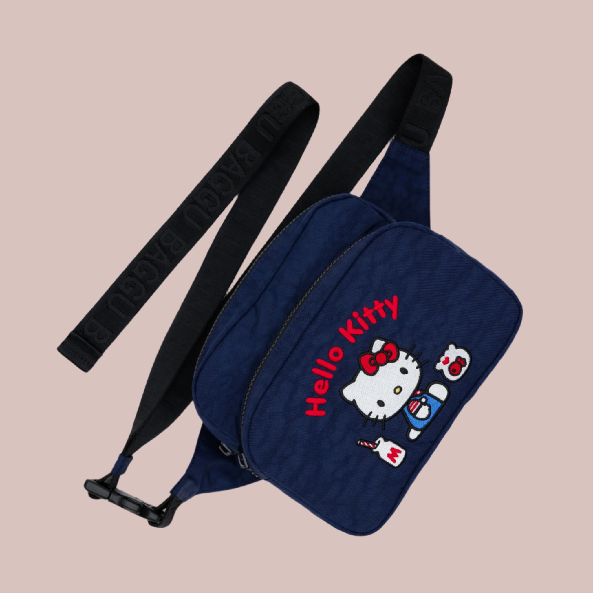 A navy blue nylon fanny pack with a black strap and an embroidered Hello Kitty milkshake design with red text that reads, &#39;Hello Kitty&#39;. 