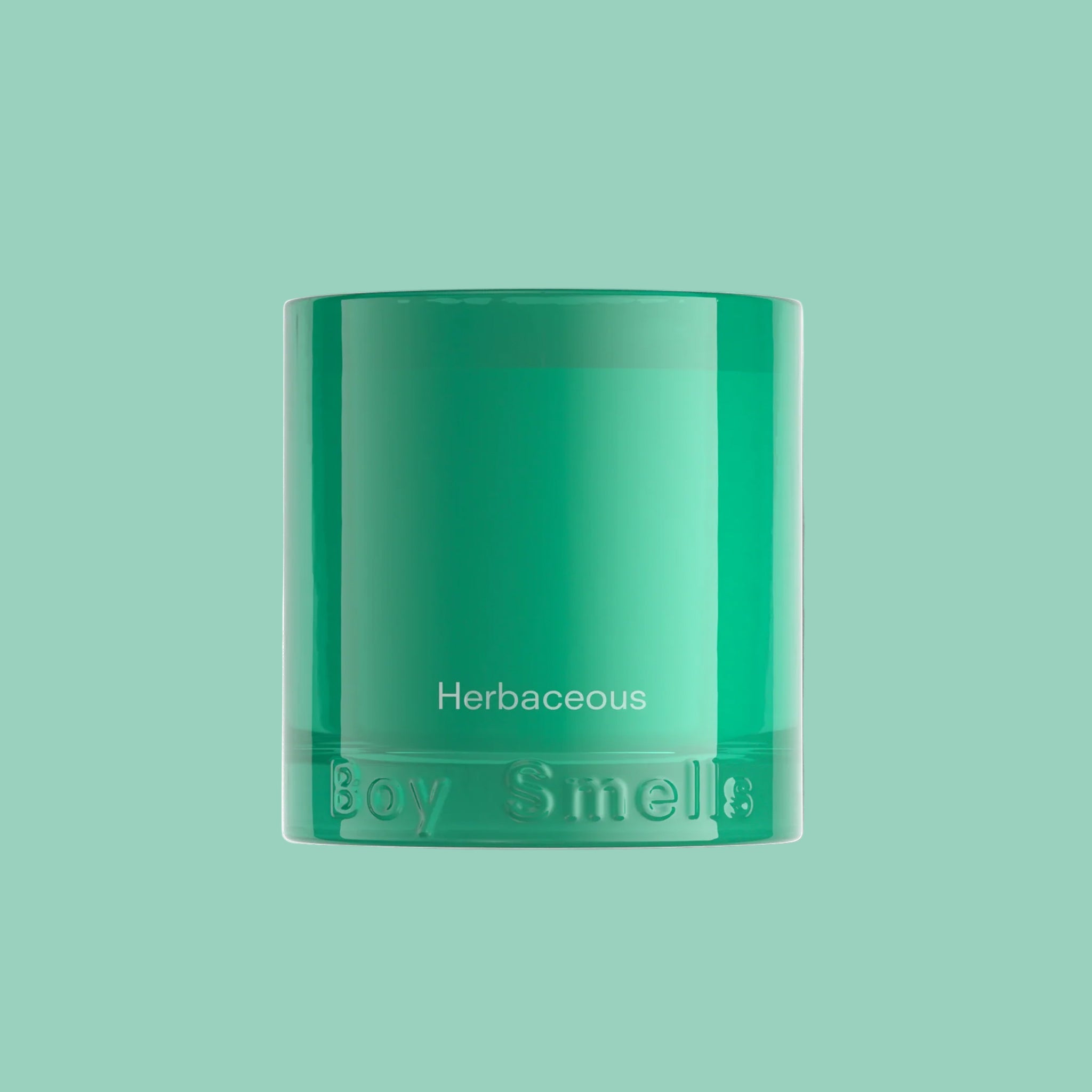 A teal glass candle with text that reads, 'Herbaceous Boy Smells'. 