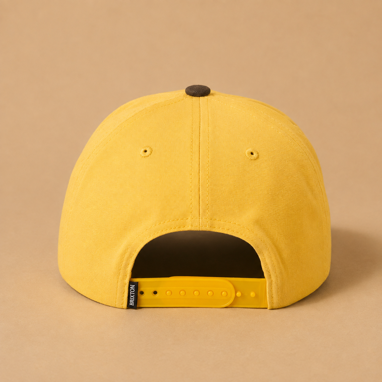 the back of a yellow and brown snapback baseball hat. 