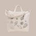 An ivory canvas bag with black shell embroidery. 