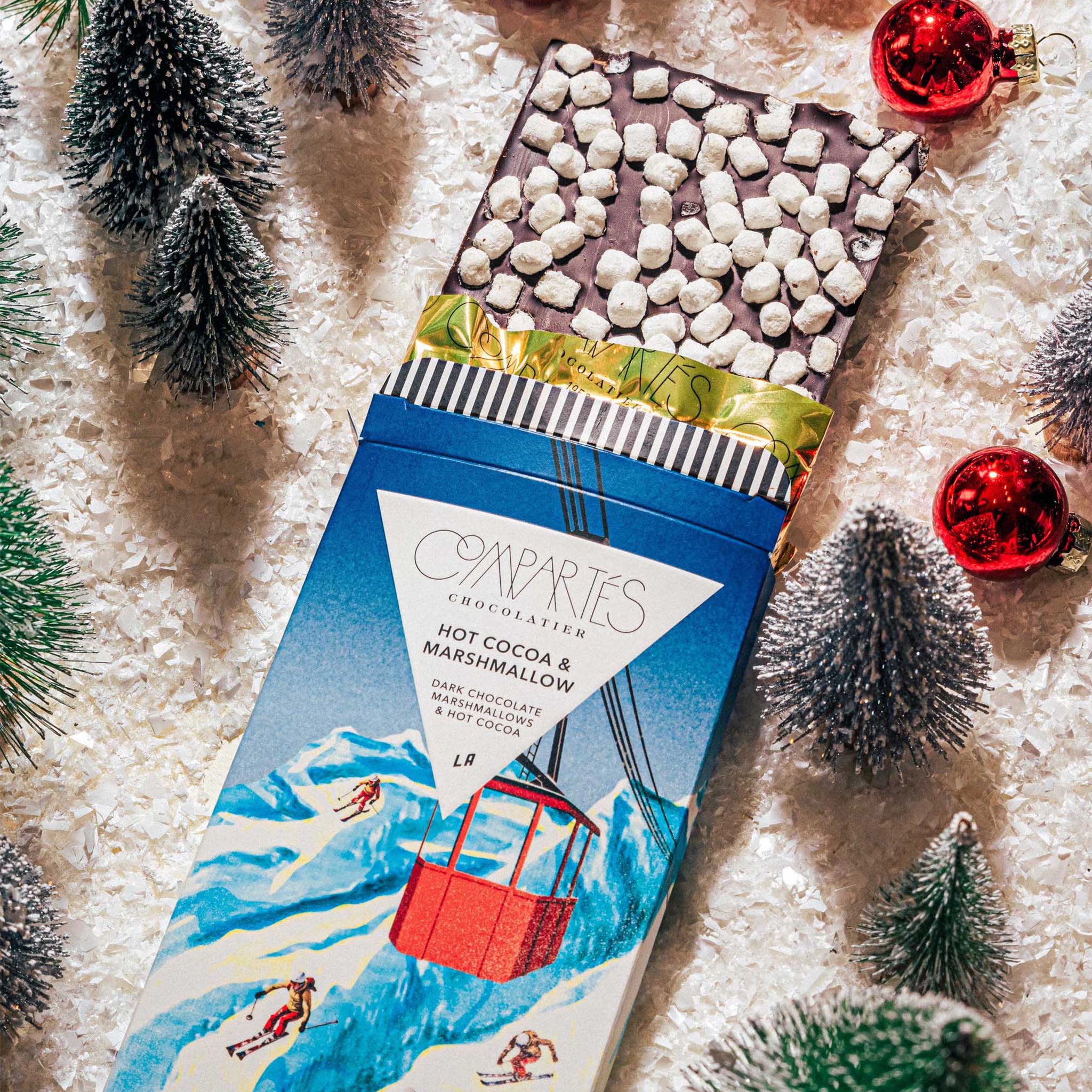rectangle chocolate bar with packaging that features a mountain and skiers in red outfits along with text at the top that reads, "Compartes Hot Cocoa & Marshmallow Dark Chocolate".