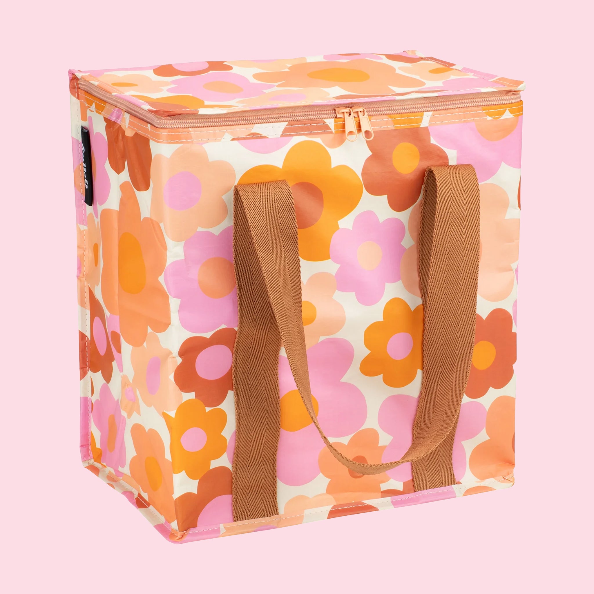 On a pink background is a orange pink and ivory floral print cooler bag. 