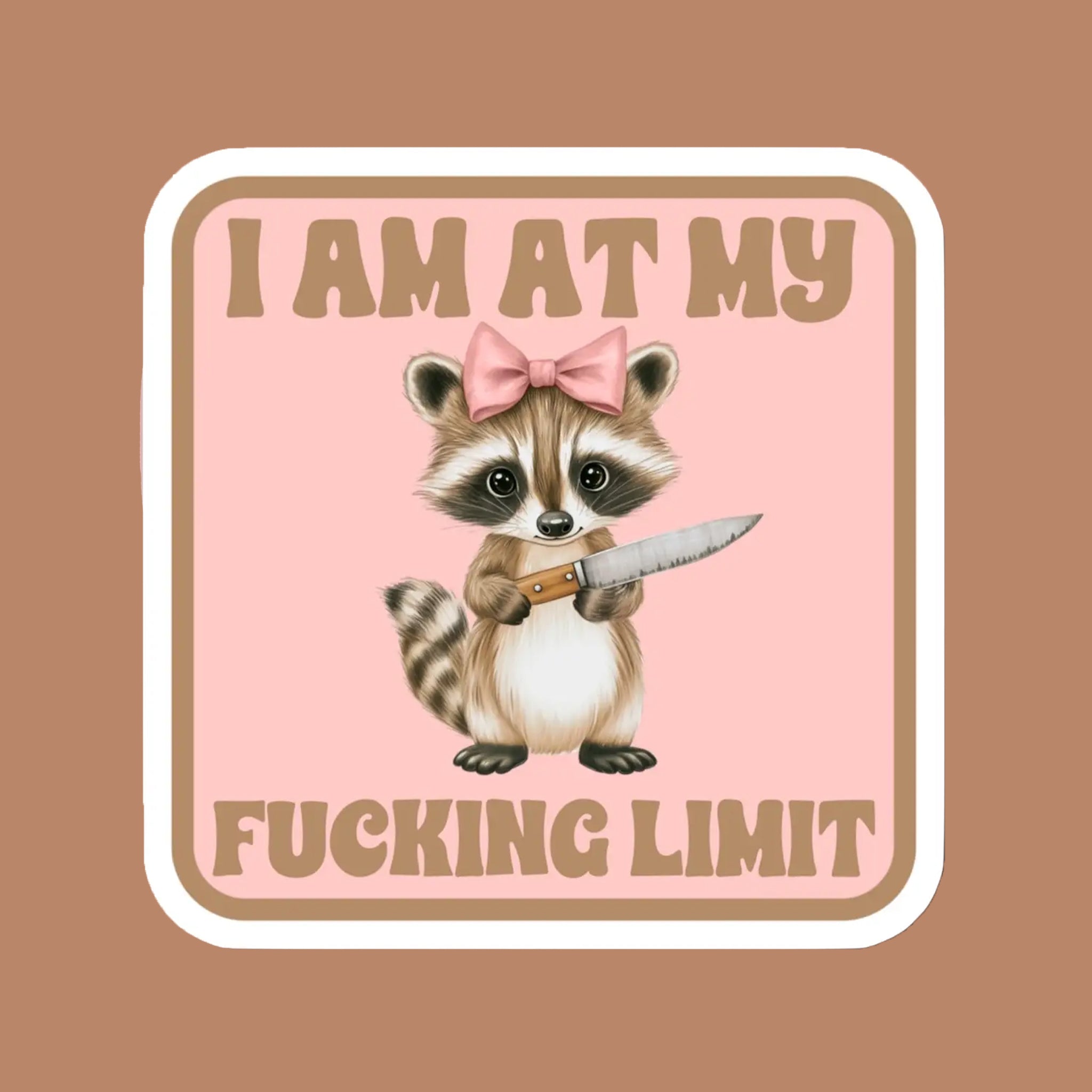 A sticker of a sweet raccoon with a pink bow holding a knife along with text that reads, "I Am At My Fucking Limit". 