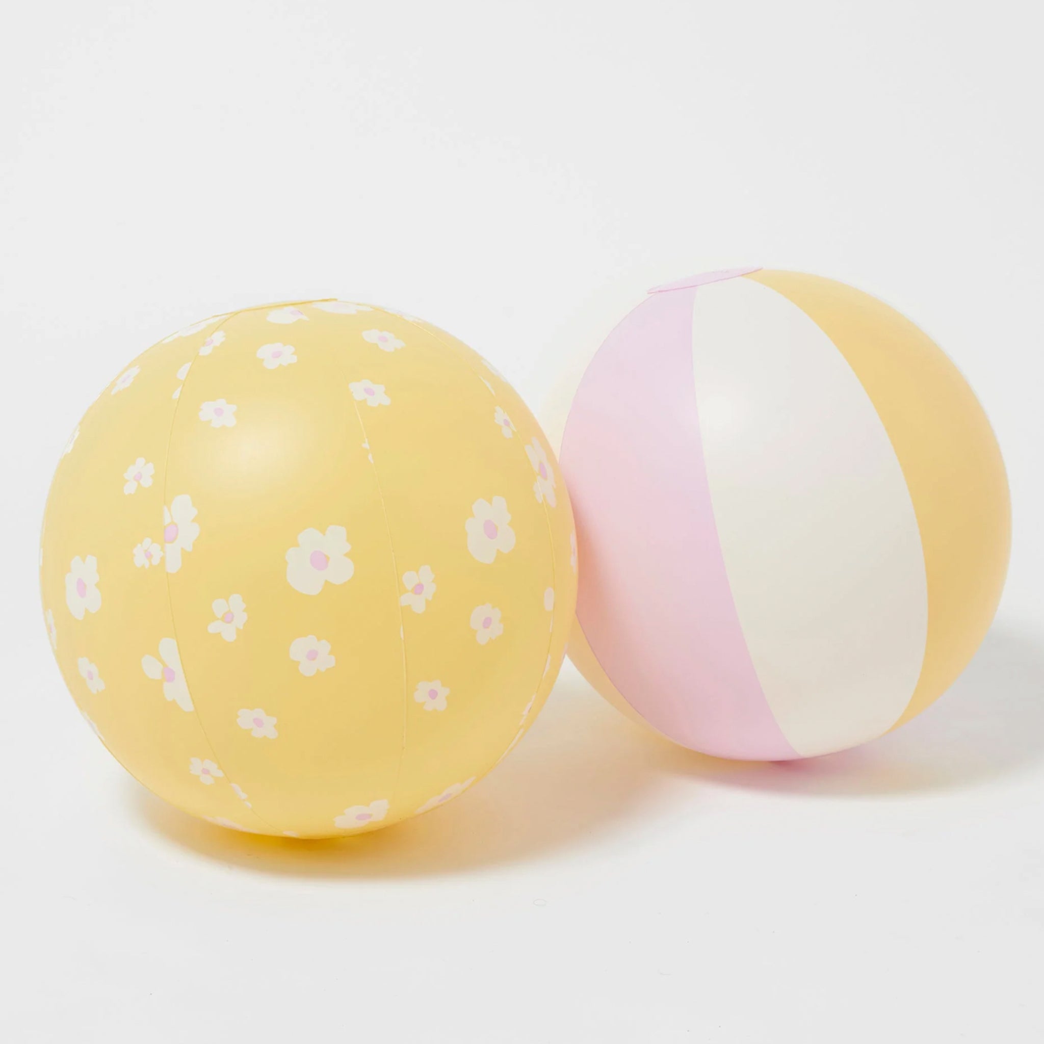 Two inflatable beach balls, one yellow floral printed and the other pink, yellow and white stripes.