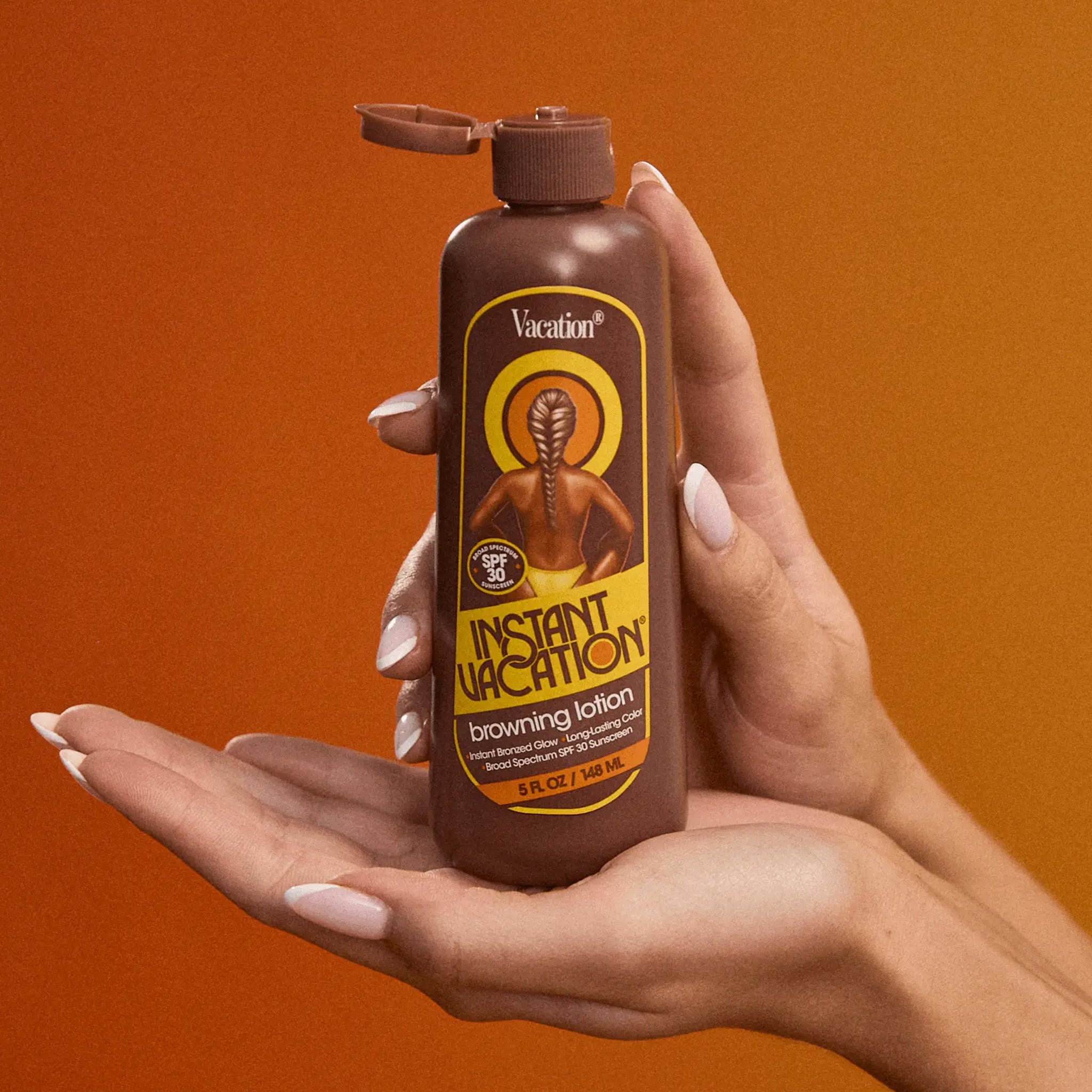 A model holding a bottle of tanning lotion.