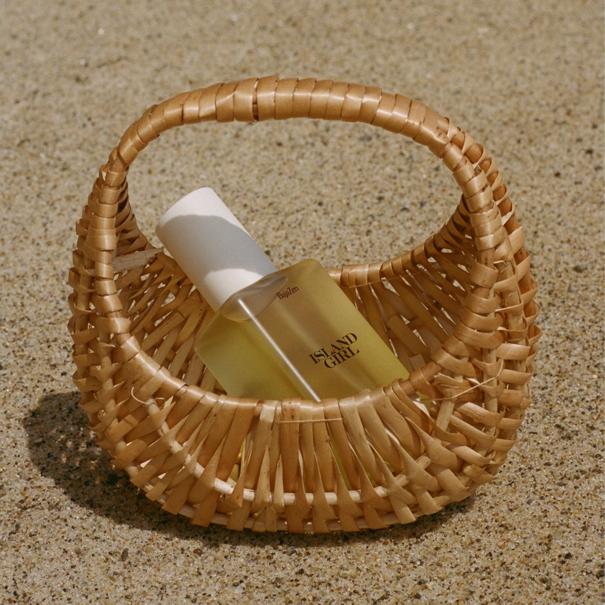A clear container of body glow oil with a white pump lid and black text that reads, "Island Girl".
