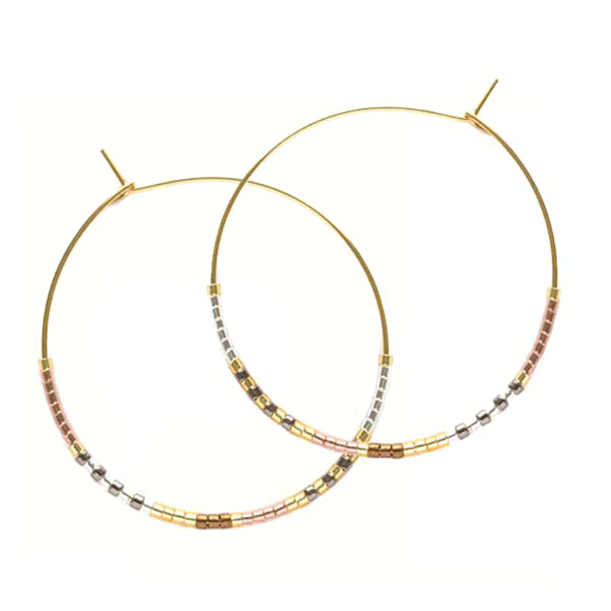 A pair of gold thin hoop earrings with neutral colored beads on the bottom half of it. 