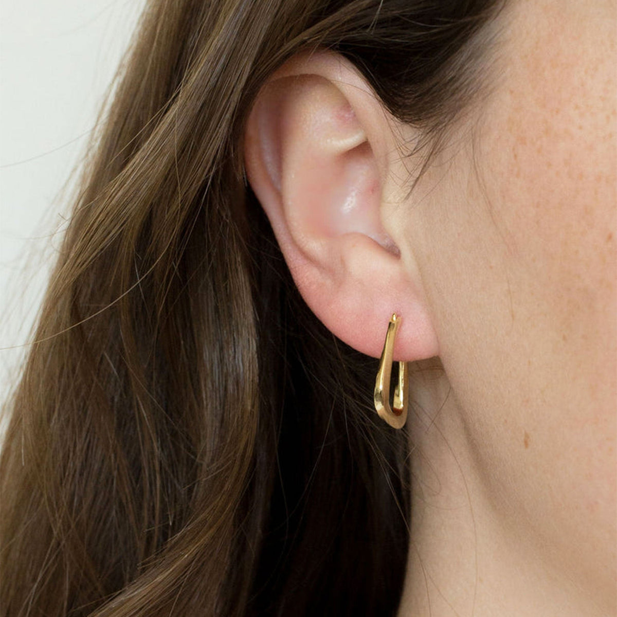 A square shaped pair of gold hoop earrings. 
