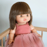 A baby doll with brown straight hair and amber colored eyes.