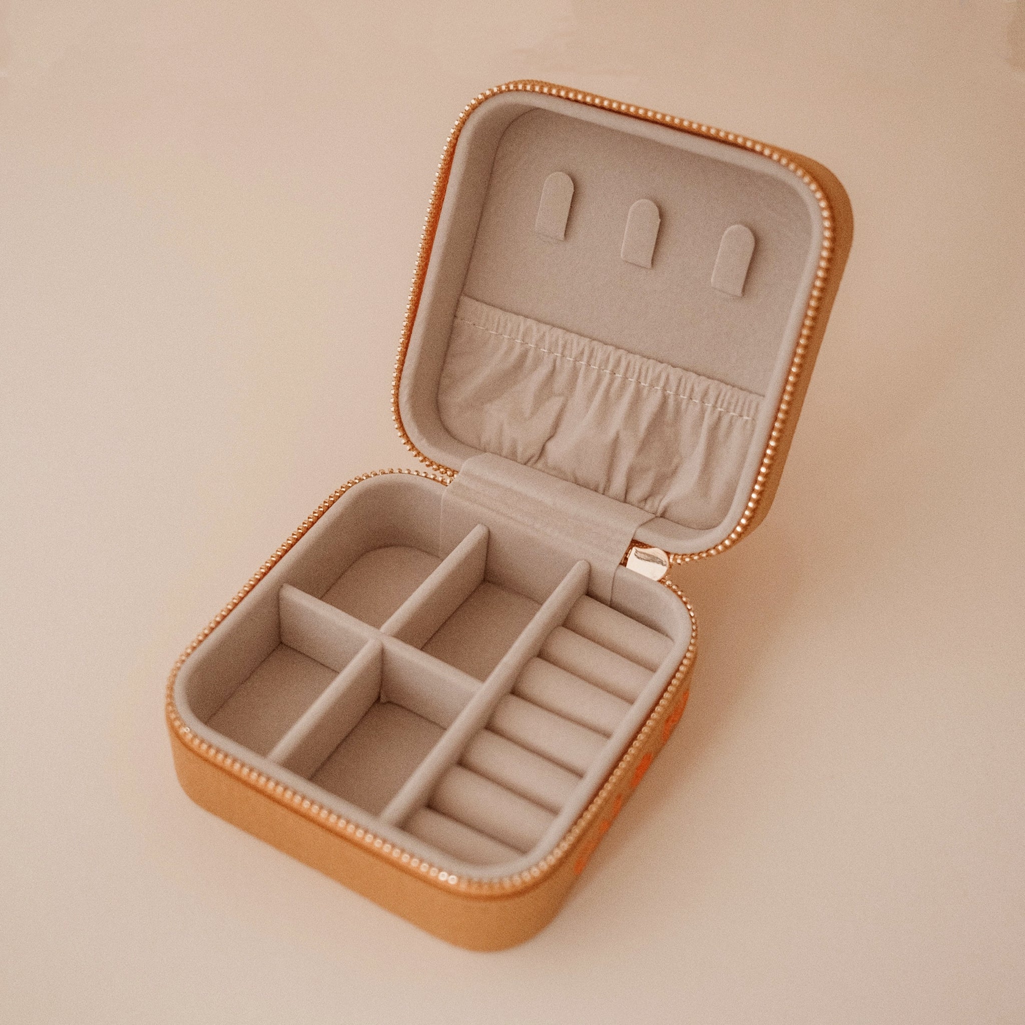 A tan jewelry case with orange flowers.