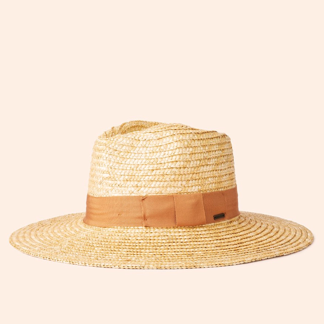On a cream background is a light honey colored straw sun hat with a tan ribbon around the base.