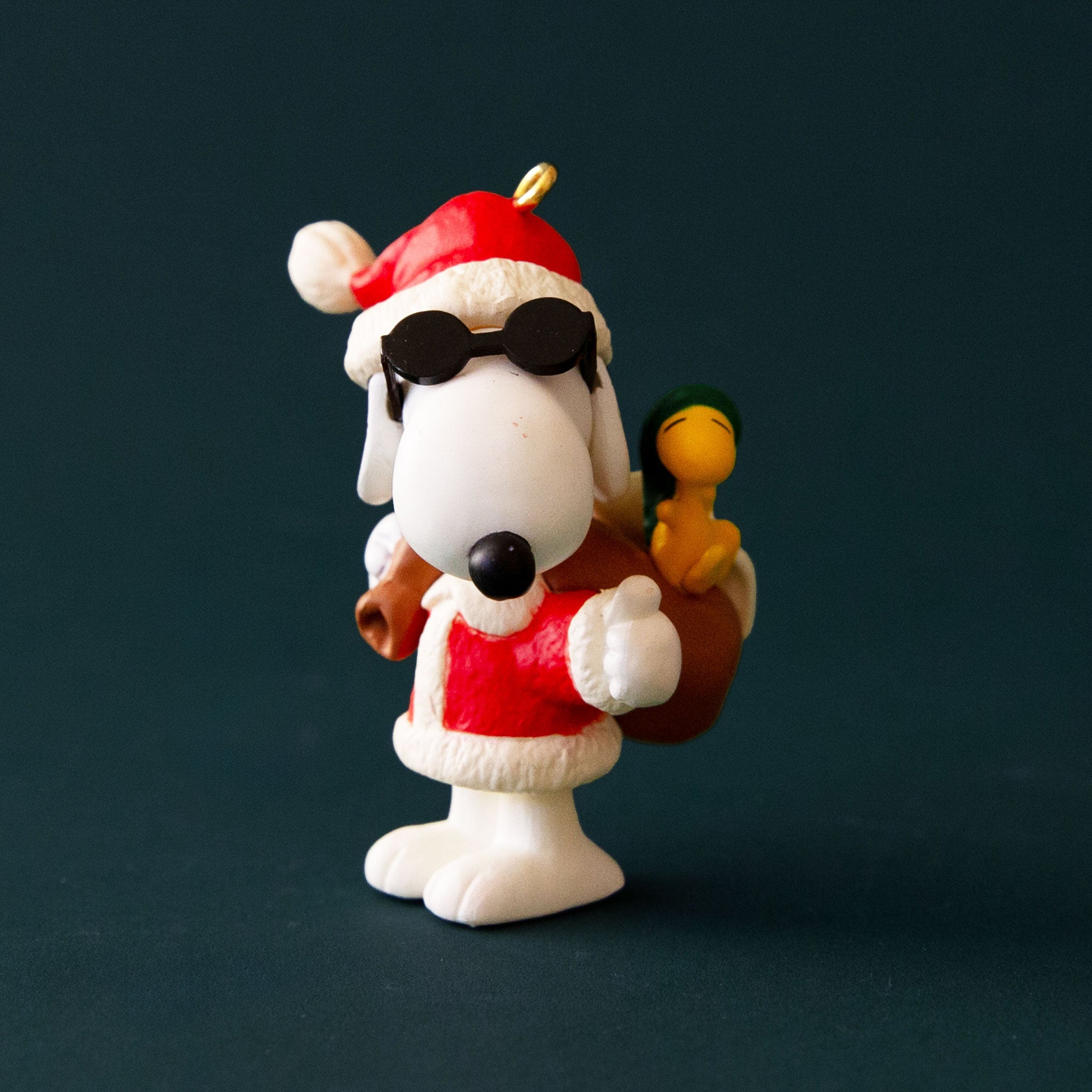 A vintage ornament in the shape of Snoopy in a Santa and sunglasses outfit. 