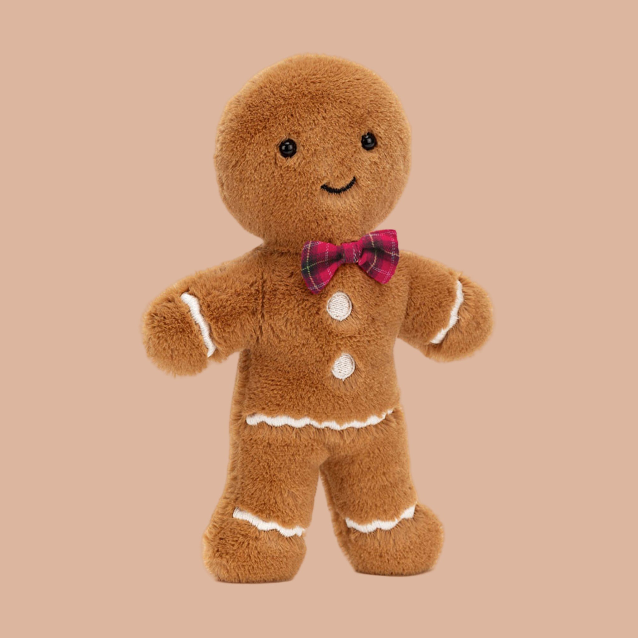 A  gingerbread man shaped stuffed toy wearing a red bow. 