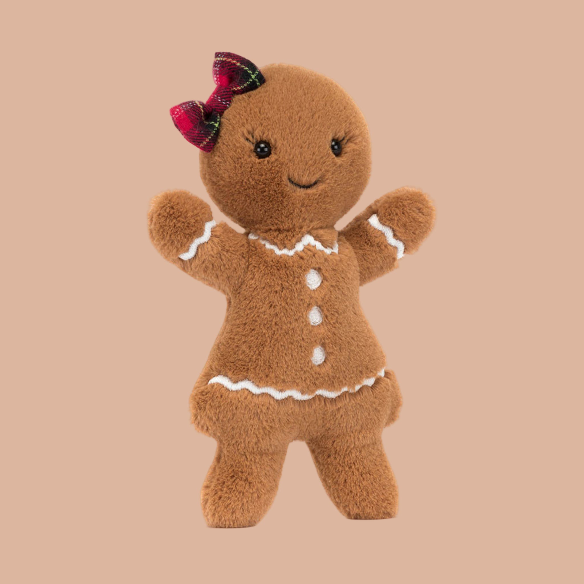 A gingerbread lady shaped stuffed toy with a red and green bow.