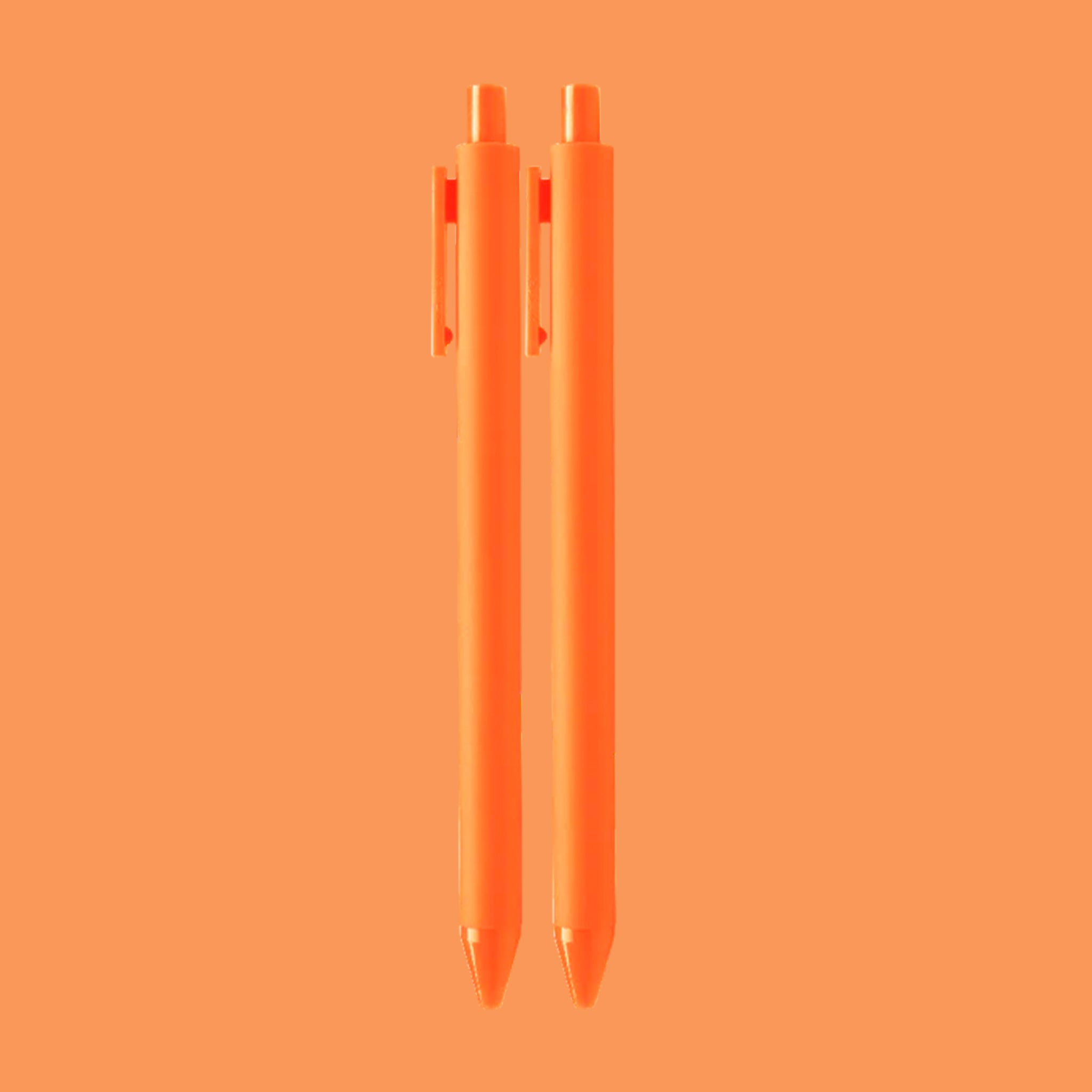 On an orange background is a pair of orange pens. 