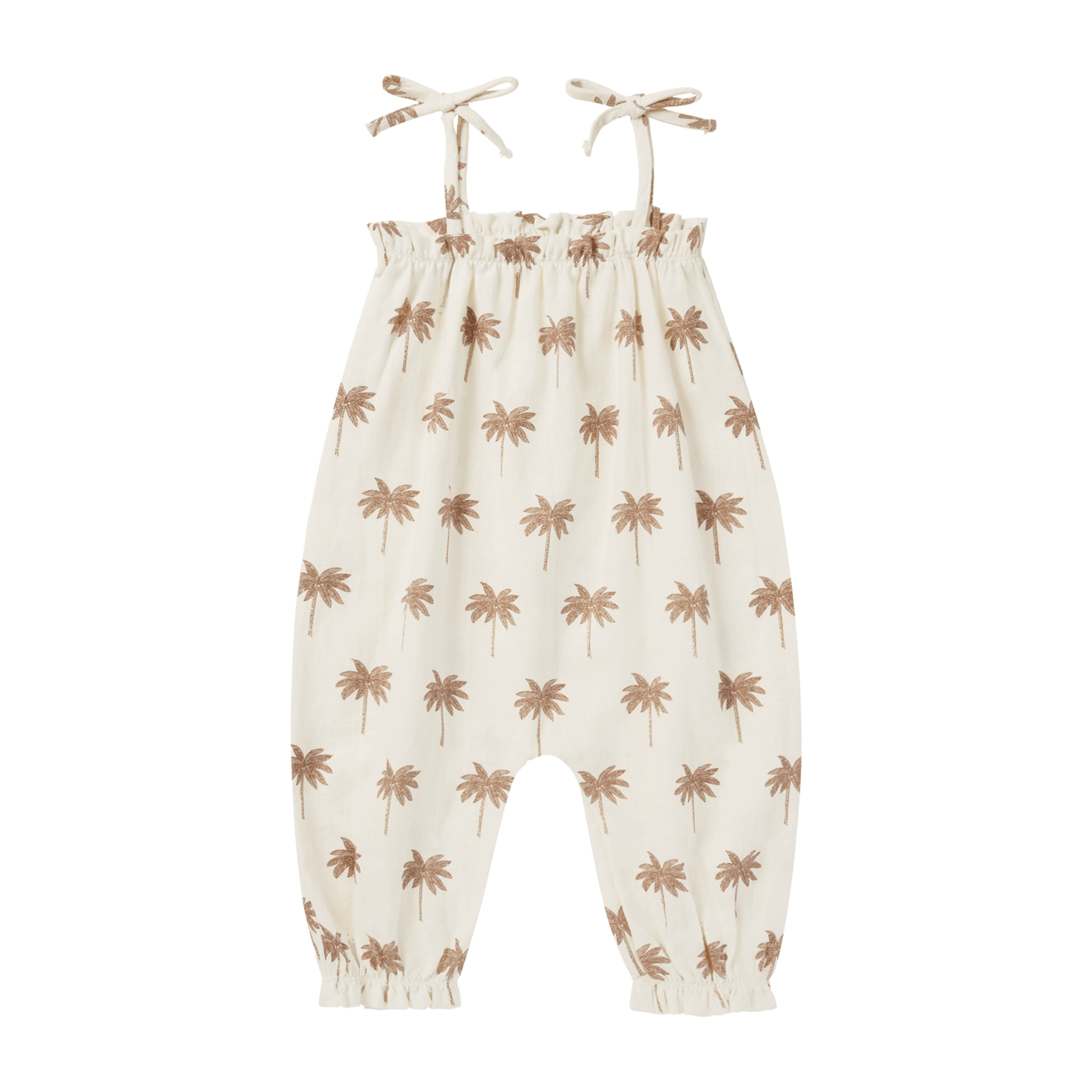 On a white background is a children&#39;s ivory jumpsuit with a neutral tan palm tree pattern and tie shoulder strap details. 