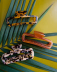 On a green background is a variety of rectangle claw clips in tortoise shades and an amber color.