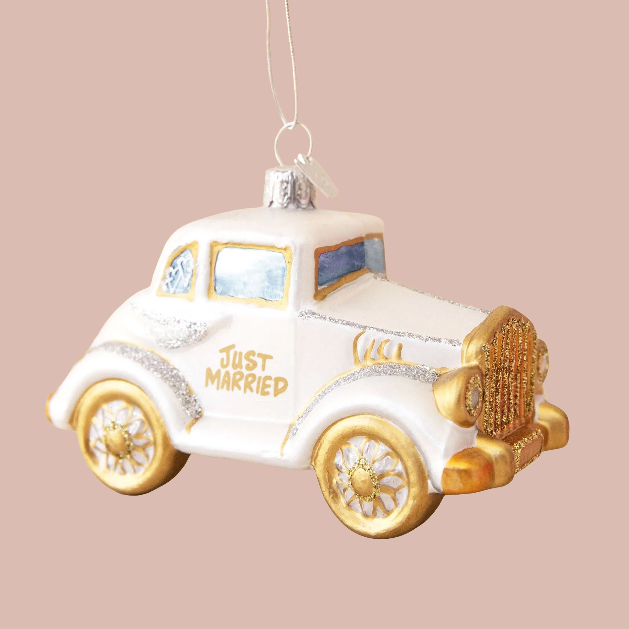 Ornament of a vintage white car with gold and silver sparkle details. The door of the car reads "Just Married" in gold lettering. 