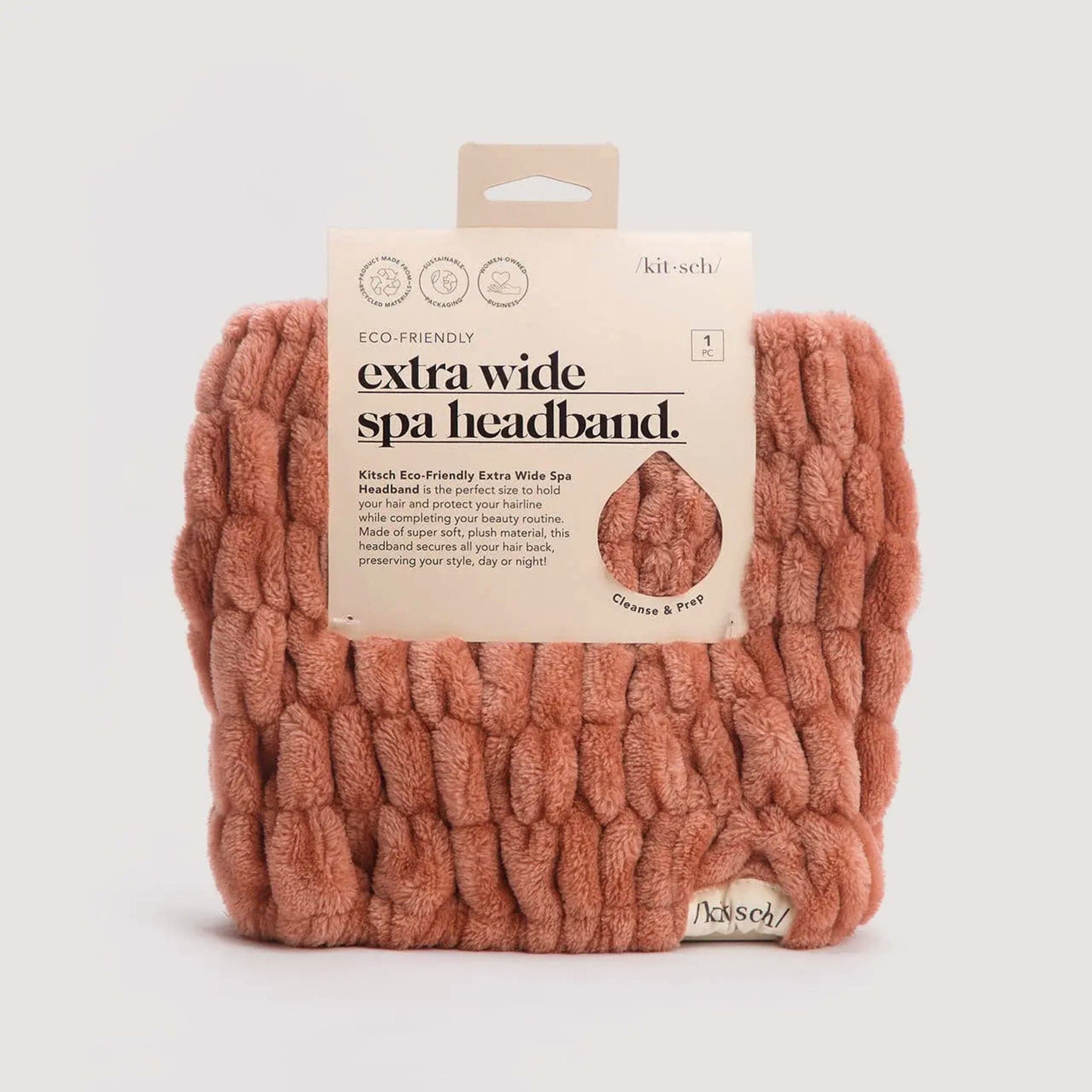 Velvety soft, pale coral headband with a scrunched texture throughout. The headband is positioned in packaging reading 'Eco-friendly, extra wide spa headband.' in black text. A small 'Kitch' label is stitched in the bottom right corner of the headband.