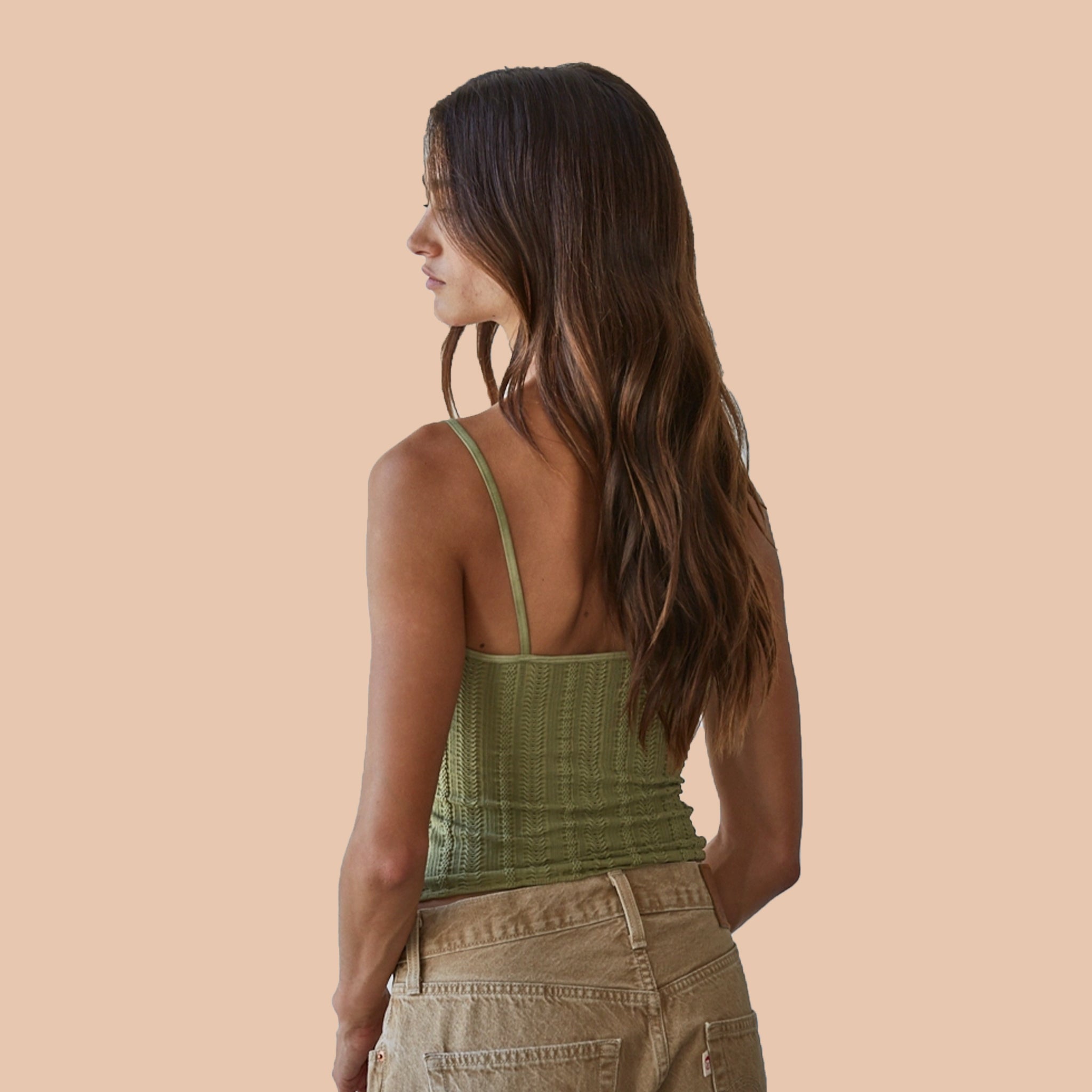 A green tank top with a v-neck, textured details and thin spaghetti straps. 