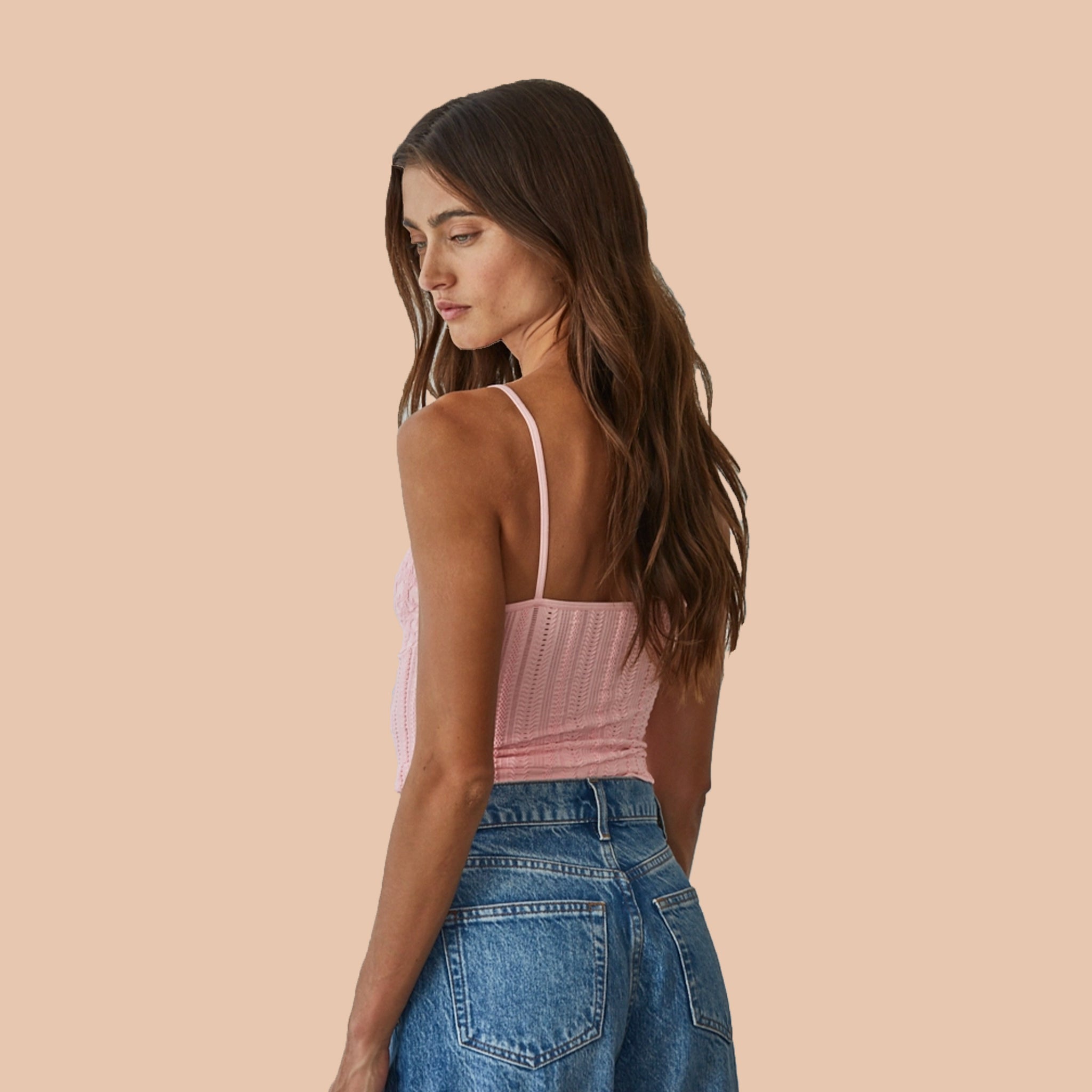 A pink tank top with a textured material and thin spaghetti straps. 